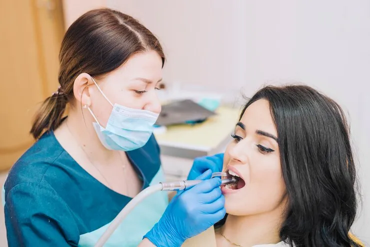 Dentist checking a female s teeth Dentist checking a female s teeth